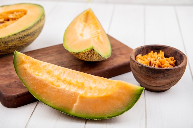 Vista dall'alto di fette di melone cantalupo fresco sul bordo della cucina in legno su legno bianco