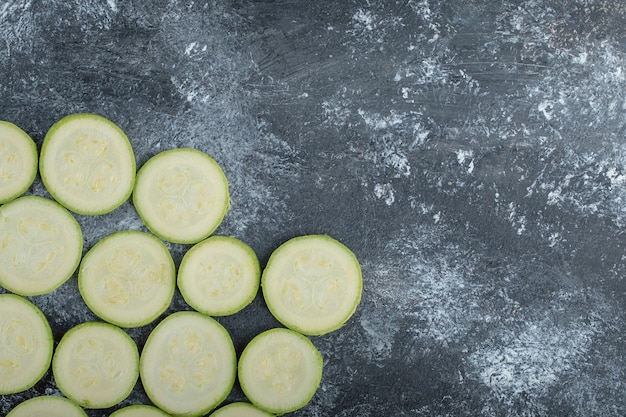 Vista dall'alto di fette di zucchine fresche su sfondo grigio.