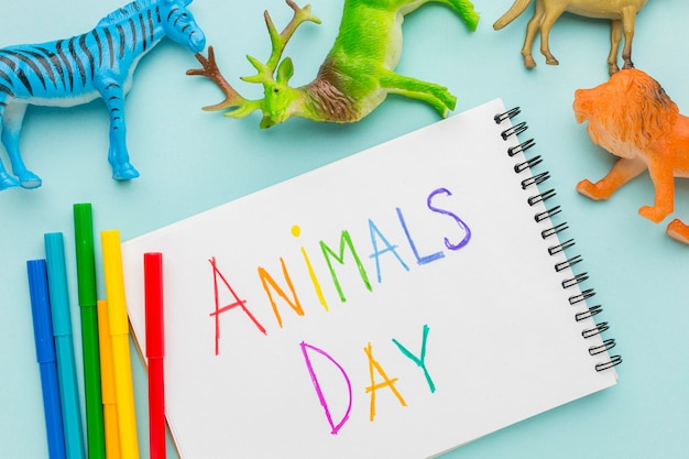 Vista dall'alto di figurine di animali e scritte colorate sul taccuino per la giornata degli animali