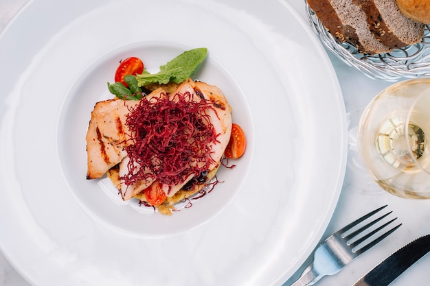 Vista dall'alto di filetto di pollo alla griglia servito con bulgur e verdure e vino bianco