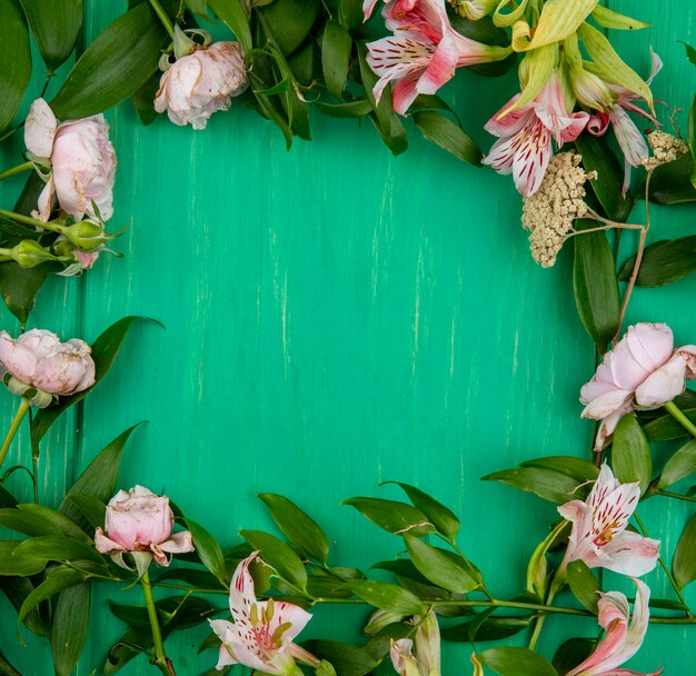 Vista dall'alto di fiori rosa chiaro con rami di foglia su una superficie verde