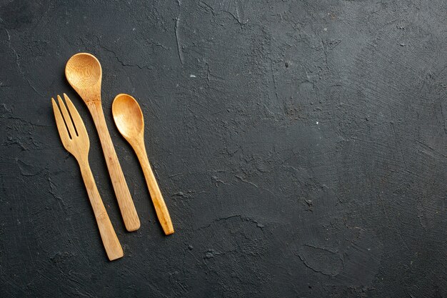 Vista dall'alto di forchetta di legno e cucchiai sul tavolo scuro con posto libero
