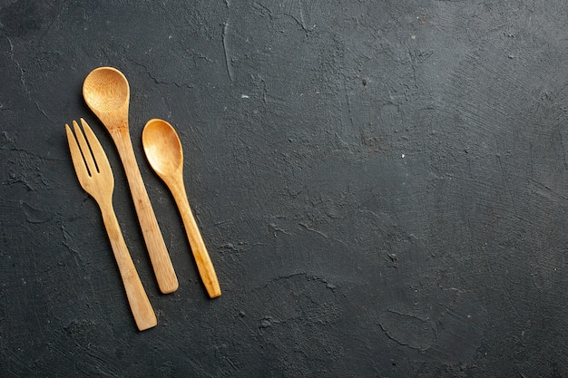 Vista dall'alto di forchetta di legno e cucchiai sul tavolo scuro con posto libero