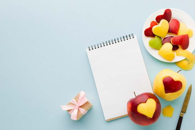 Vista dall'alto di forme di cuore di frutta con notebook e presente