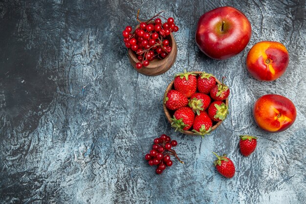 Vista dall'alto di fragole rosse fresche con pesche e mele sulla superficie scura