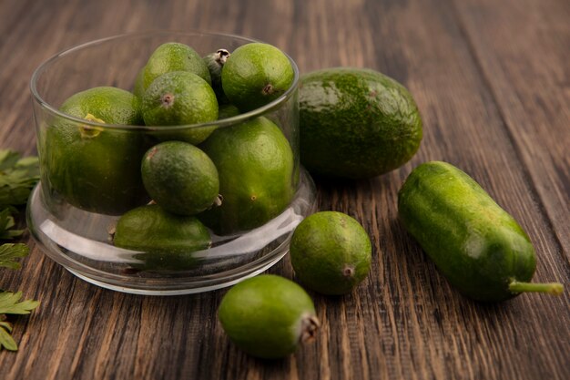 Vista dall'alto di fresche e mature feijoas su una ciotola di vetro con avocado cetriolo e feijoas isolato su una superficie in legno