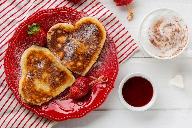 Vista dall'alto di frittelle a forma di cuore con fragole