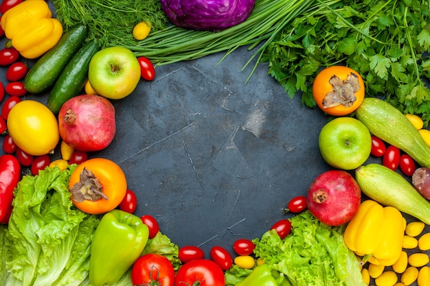 Vista dall'alto di frutta e verdura lattuga pomodori zucchine cetriolo aneto pomodorini peperoni melograno cachi mela posto libero al centro