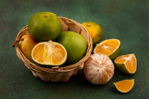 Vista dall'alto di frutta fresca come mandarini mele pera kiwi su un secchio con mandarini tagliati a metà isolati