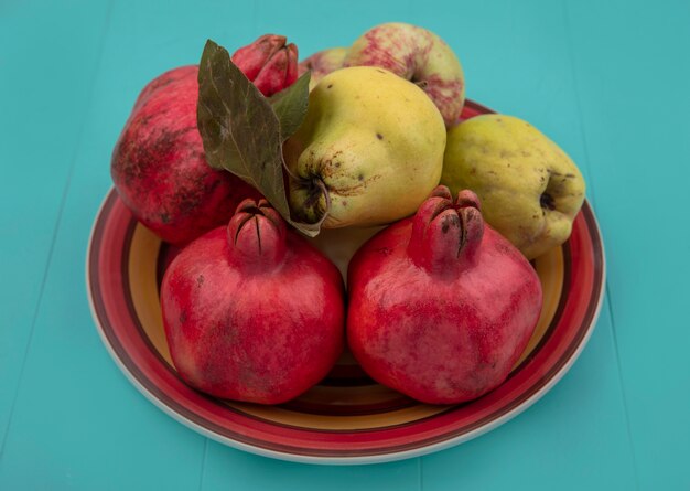 Vista dall'alto di frutta fresca come mele cotogne melograno e mele su una ciotola su sfondo blu