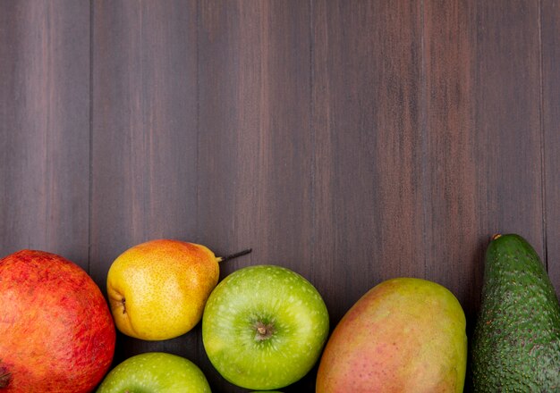 Vista dall'alto di frutta fresca come pera melograno mele mango isolato su legno