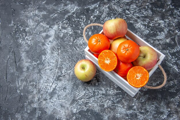 Vista dall'alto di frutta fresca in scatola di bastoncini di cannella su sfondo scuro con posto libero