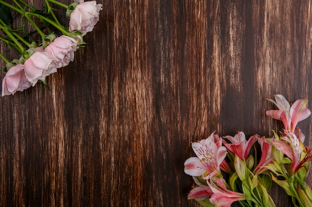 Vista dall'alto di gigli rosa con rose rosa su una superficie di legno