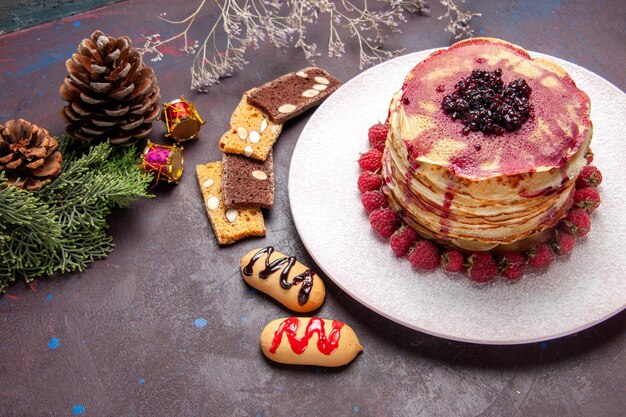 Vista dall'alto di gustosi pancake alla frutta con gelatina e fragole sul tavolo scuro