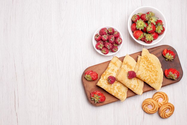 Vista dall'alto di gustosi pancake dolci con frutta su bianco