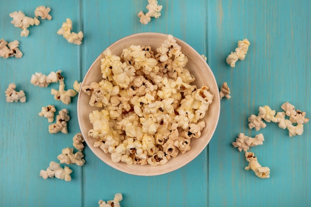 Vista dall'alto di gustosi popcorn su una ciotola su un tavolo di legno blu
