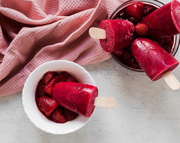 Vista dall'alto di gustosissimi ghiaccioli in tazza e vaso con fragole