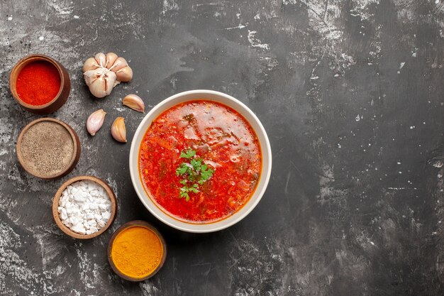 Vista dall'alto di gustoso borsch con condimenti su superficie scura