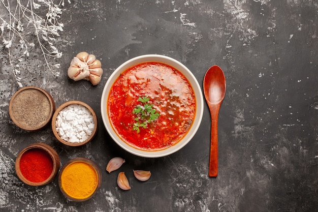 Vista dall'alto di gustoso borsch con condimenti su superficie scura