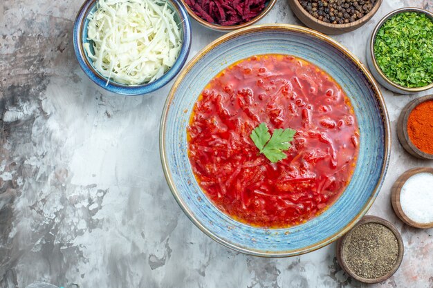 Vista dall'alto di gustoso borsch con condimenti sulla superficie bianca