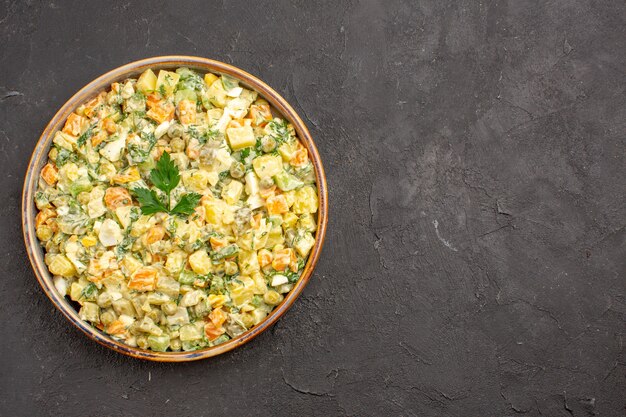 Vista dall'alto di insalata di maionese con diverse verdure sulla superficie scura