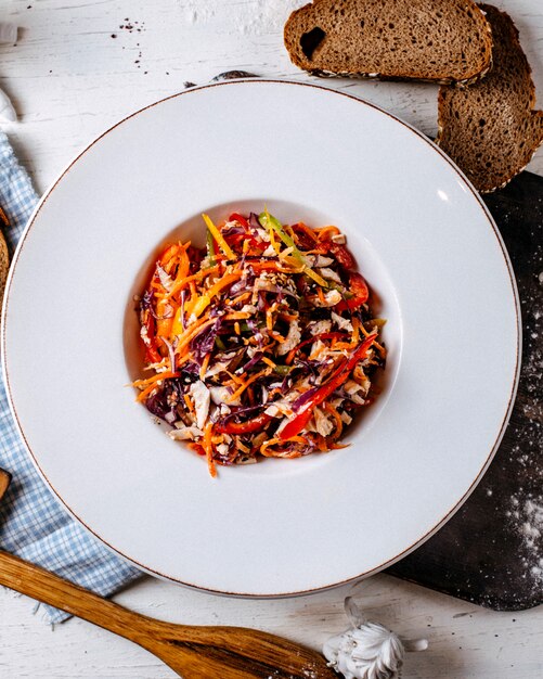 Vista dall'alto di insalata di pollo con cavolo tritato e peperoni colorati in un piatto