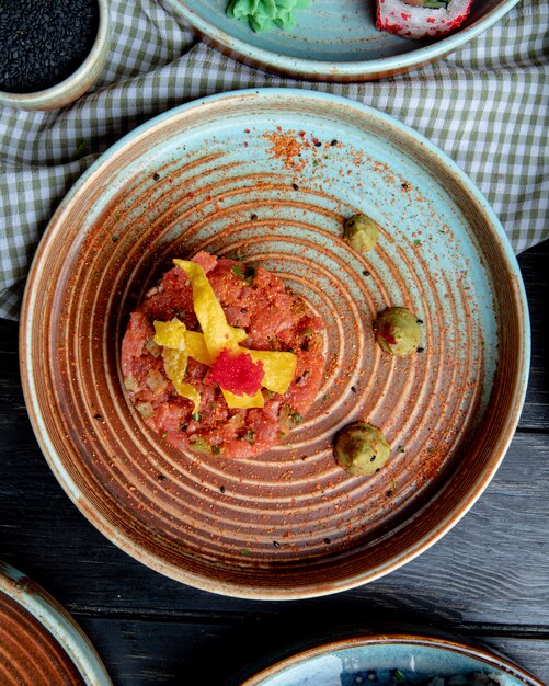 Vista dall'alto di insalata di salmone con avocado e salsa wasabi su un piatto su tessuto plaid