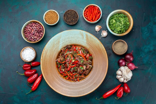 Vista dall'alto di insalata di verdure di carne affettata all'interno del piatto con condimenti di verdure sull'ingrediente vegetale del pasto di cibo di insalata di tavola blu scuro