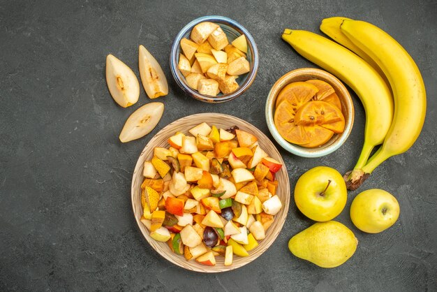 Vista dall'alto di insalata fruttata con frutta fresca a fette sullo sfondo grigio scuro