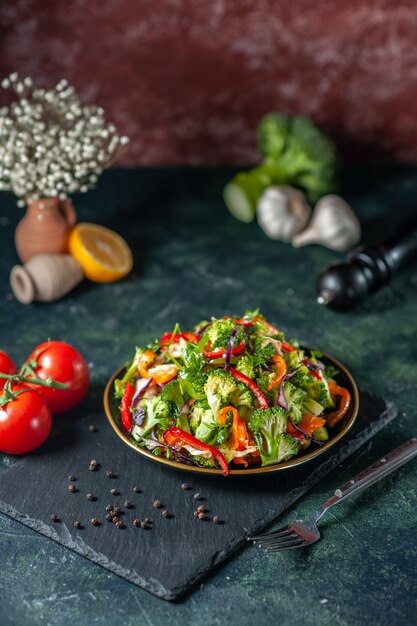 Vista dall'alto di insalata vegana con ingredienti freschi in un piatto su tagliere nero