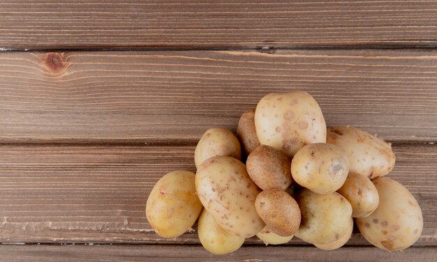 Vista dall'alto di intere patate sul lato destro e sfondo in legno con spazio di copia