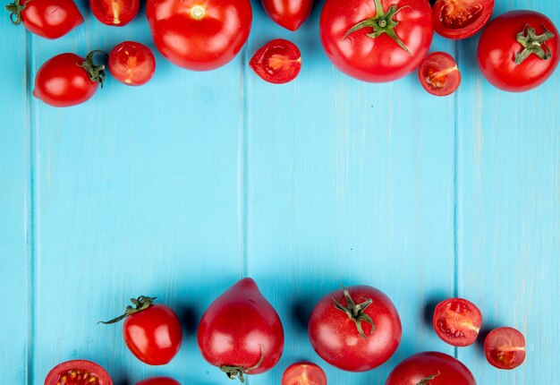 Vista dall'alto di interi e tagliare i pomodori sulla superficie blu con spazio di copia