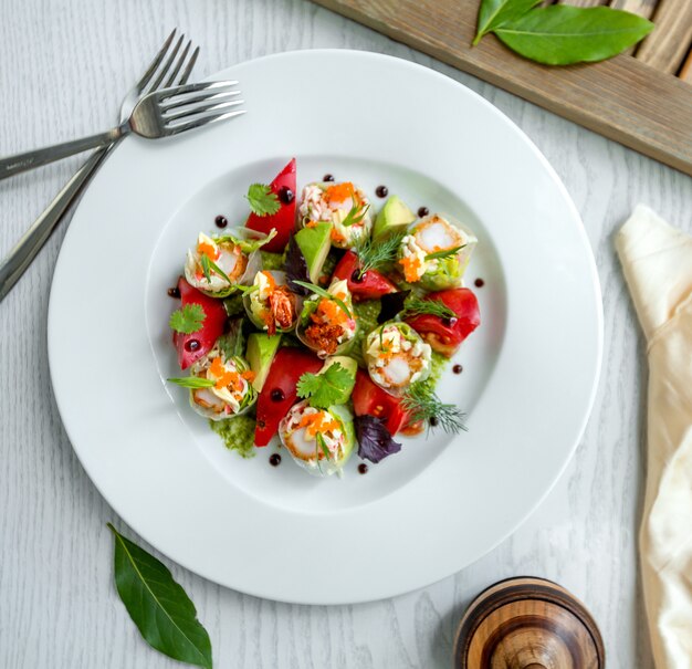 Vista dall'alto di involtini primavera tagliati a metà con gamberi, lattuga servita con avocado