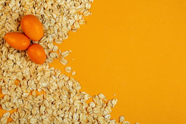 Vista dall'alto di kumquat su fiocchi d'avena con copia spazio su jpg giallo