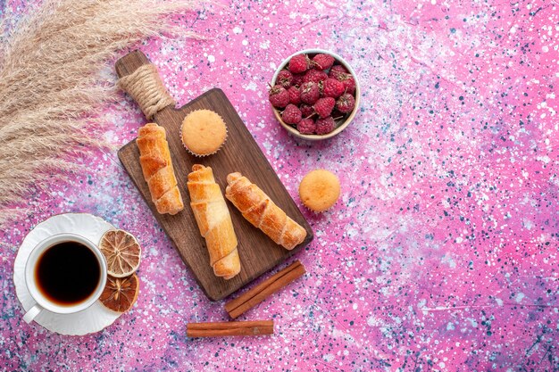 Vista dall'alto di lamponi freschi gustosi all'interno del piatto bianco con ciambelle di tè e cannella sulla superficie rosa