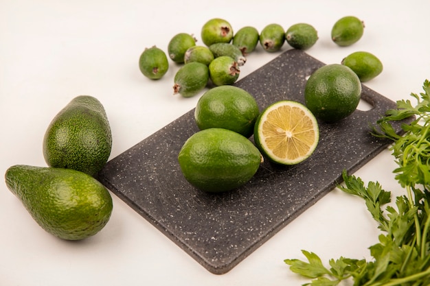 Vista dall'alto di lime aspro su una tavola da cucina con feijoas e avocado isolati su una parete bianca