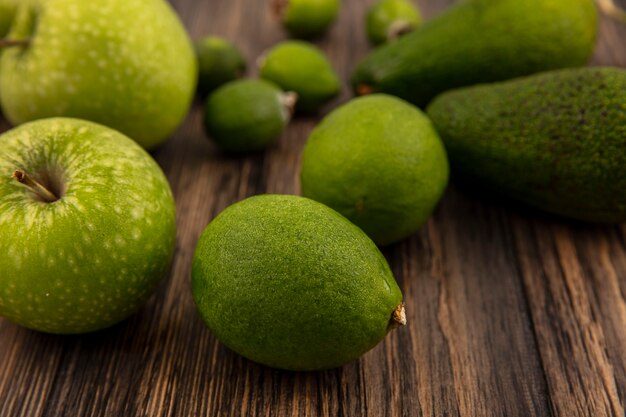 Vista dall'alto di limette fresche con mele verdi e feijoas isolati su uno sfondo di legno