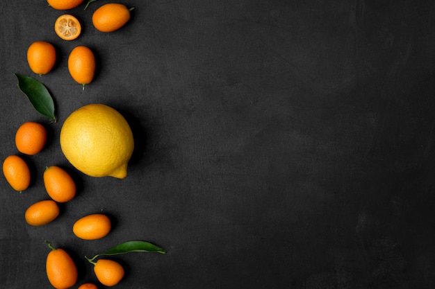 Vista dall'alto di limone e kumquat sul lato sinistro sulla superficie nera