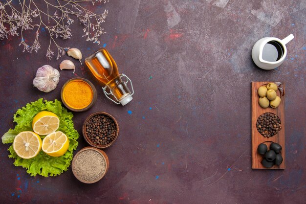 Vista dall'alto di limone fresco a fette con insalata verde e olive su nero