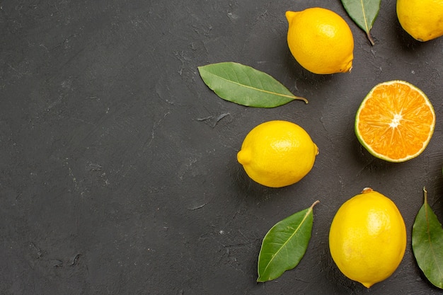 Vista dall'alto di limoni freschi e aspri foderati sul tavolo scuro agrumi giallo lime frutti