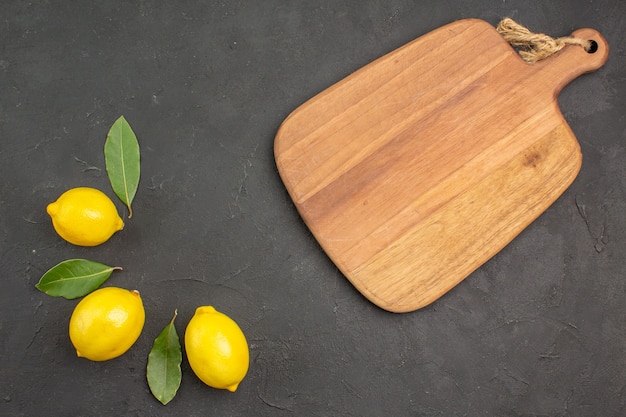 Vista dall'alto di limoni freschi e aspri rivestiti su tavola scura frutta giallo lime agrumi