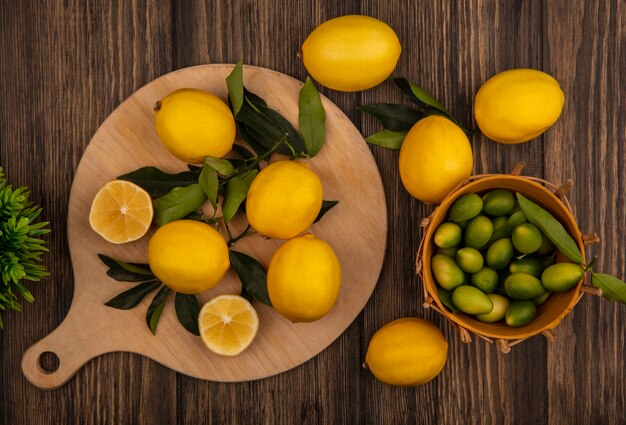 Vista dall'alto di limoni freschi isolati su una tavola da cucina in legno con kinkans su un secchio su uno sfondo di legno