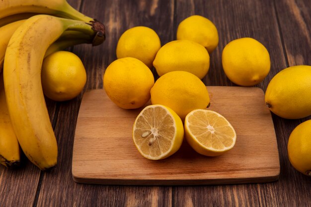 Vista dall'alto di limoni freschi su una tavola da cucina in legno con limoni e banane isolate su una superficie in legno