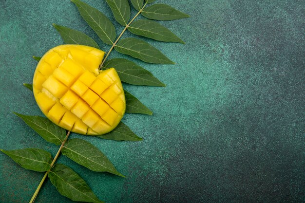 Vista dall'alto di mango fresco a fette con foglia sul verde