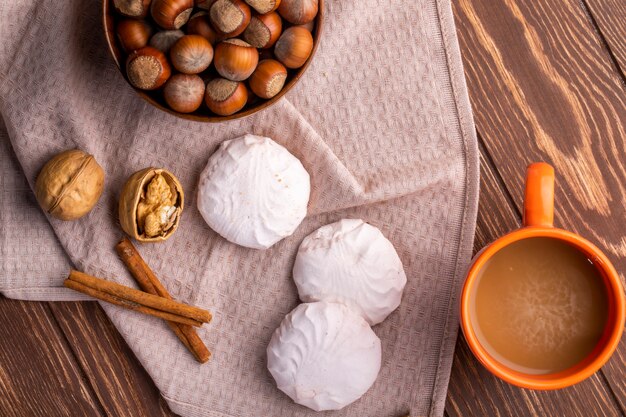 Vista dall'alto di marshmallows zephyr bianchi nocciole in una ciotola e una tazza di bevanda al cacao su un legno