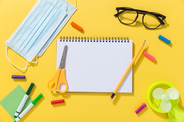 Vista dall'alto di materiale scolastico con occhiali e notebook