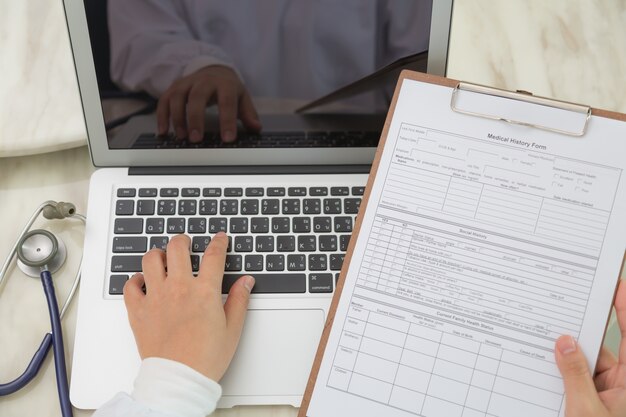 Vista dall&#39;alto di medico utilizzando un computer portatile e un blocco per appunti