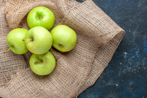 vista dall'alto di mele verdi fresche pastose e succose acide sulla scrivania blu scuro, spuntino alimentare con vitamine per la salute della frutta