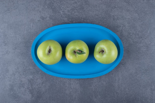 Vista dall'alto di mele verdi organiche fresche sul piatto di legno blu