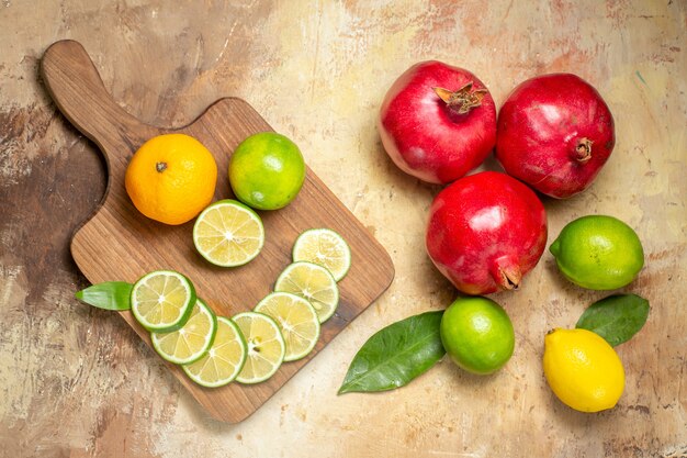 Vista dall'alto di melograni rossi freschi e limoni tagliati interi e tritati sul tabellone su sfondo a colori misti